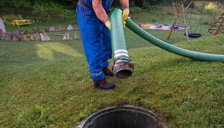 Technicien en tenue professionnelle pompant une fosse septique